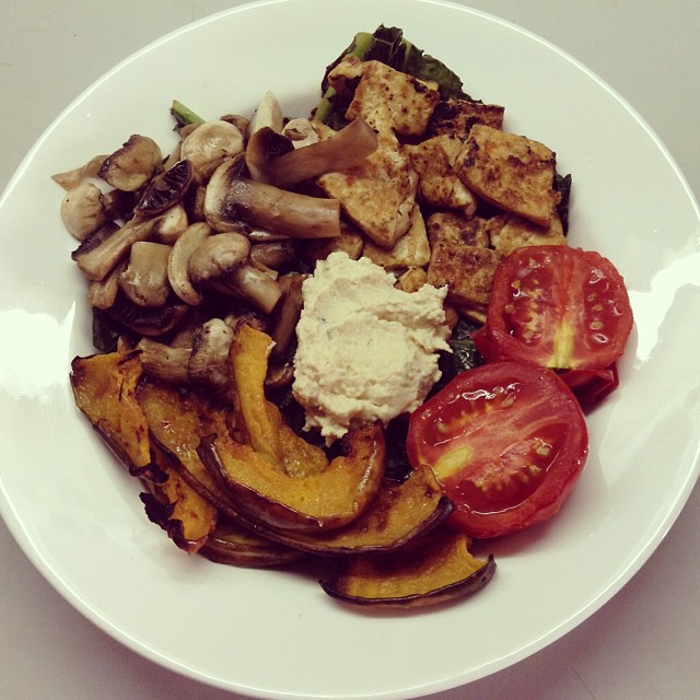 A bed of sautéed kale topped with ponzu tofu, grilled mushrooms pumpkin & tomatoes, and a dollop of hummus